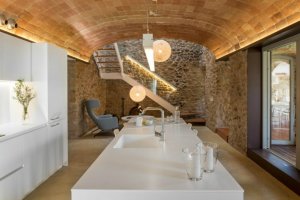 cucina bianca con soggiorno e parete in pietra