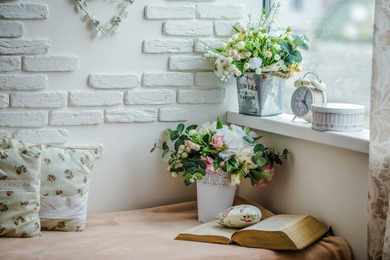 angolo lettura accostato contro la parete con cuscini e fiori