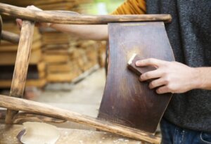 Uomo usa tecnica decapaggio su sedia in legno