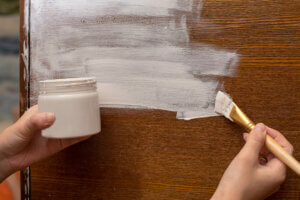 Ragazza applica il chalk paint su superficie in legno