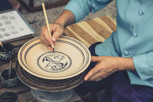 Artista decora un piatto artigianale.