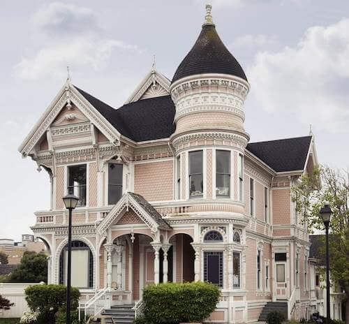 Casa vittoriana con facciata di colore rosa e bianco e tetti neri.