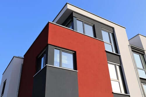 Esterno di una casa color terra rossa, grigio e bianco.