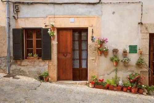 Facciate di case rustiche. Facciata in cemento abbellita con vasi di fiori.