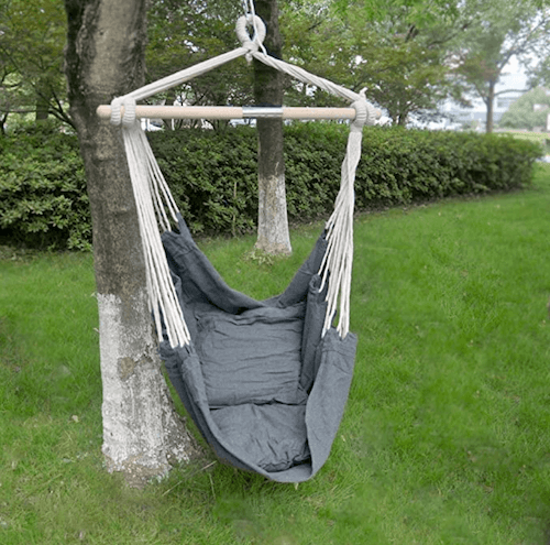 Poltrona sospesa appesa su un albero in giardino.