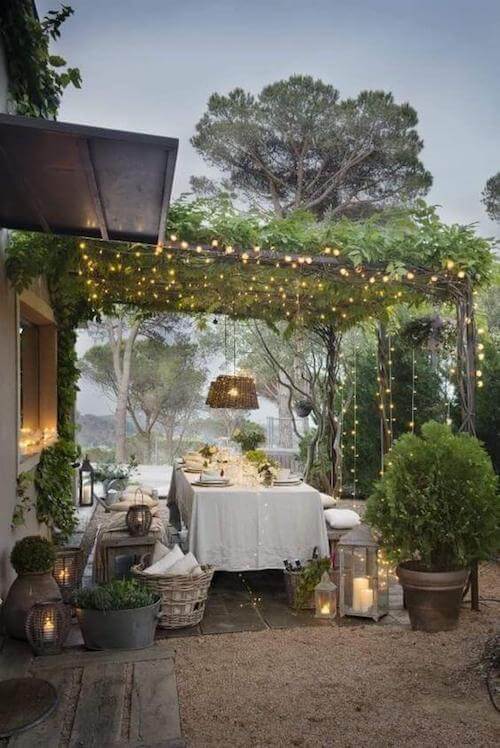 Zona esterna per il pranzo sotto un pergolato illuminato da candele e luci a led.