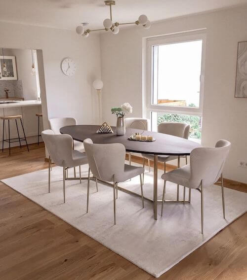 Tavolo ovale e sedie bianche con elementi dorati.