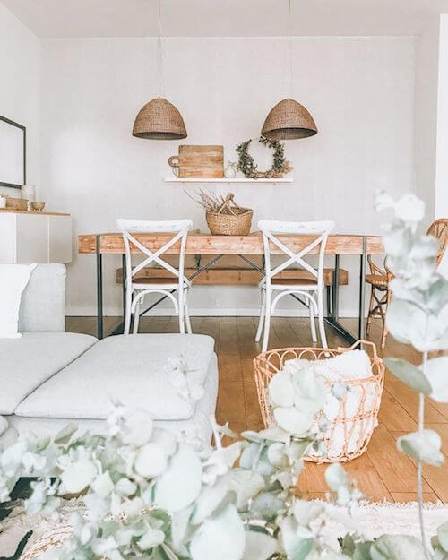 Tavolo in legno massello, sedie bianche e lampade in fibra naturale.