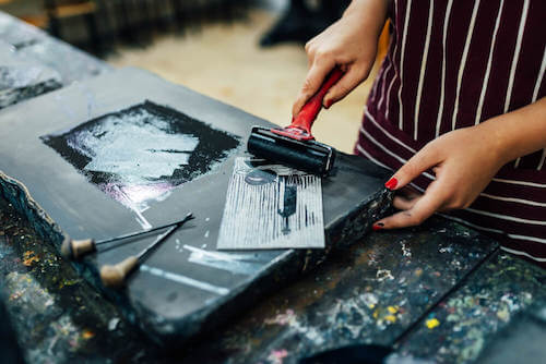 Donna che dipinge una tavola di legno.