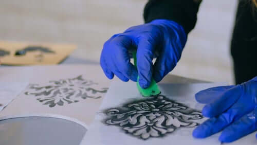 Persona che pittura un motivo decorativo stencil utilizzando una spugna.