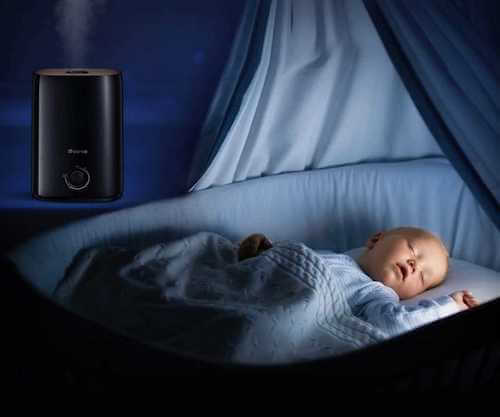 Neonato che dorme in una culla in una stanza dove c'è un umidificatore acceso.