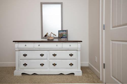 Credenza bianca con sopra uno specchio.