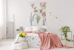 Letto matrimoniale con coperta rosa e fiori gialli.
